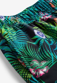 Tessuto nero con un vivace motivo floreale caratterizzato da foglie verdi e fiori multicolori. Vita elasticizzata con texture arricciata.