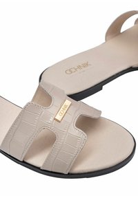 Beżowe klapki z teksturą krokodyla, z dwoma szerokimi paskami i akcentem w kolorze złotym z logo. Miękka wkładka i czarna gumowa podeszwa.