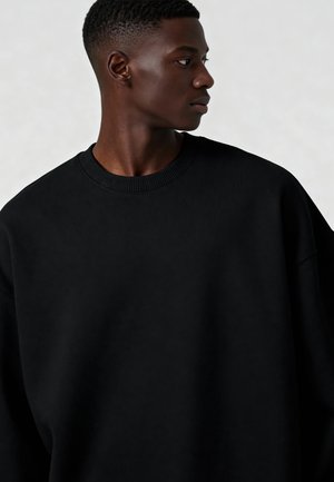Zwart oversized sweatshirt met geribbelde ronde hals en textiele stof. Bevat verlaagde schouders en een relaxte pasvorm zonder zichtbare logo's.
