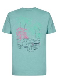 Vaaleansininen t-paita, jossa on takapuolella vintage-paketiauto, vaaleanpunainen pelastustorni ja vihreillä ääriviivoilla olevat palmupuut. Pehmeä kangas.