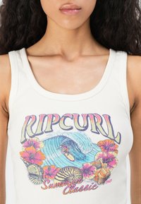 Woman wearing a white tank top with colorful "Rip Curl Summer Classic" surf-themed graphic and tropical flowers on the front.