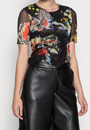 Czarny siatkowy top z kolorowymi kwiatowymi i abstrakcyjnymi wzorami, krótki rękaw oraz marszczenia po bokach. Noszony z czarnymi skórzanymi spodniami.