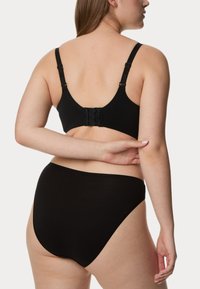 Zwarte beha met verstelbare straps en haaksluiting, gecombineerd met hooggerimpelde zwarte onderbroek. Glad stof met een naadloos ontwerp.