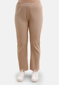 Ribbet, lysebrune bukser med elastisk talje, slim fit og lige ben design, parret med hvide sneakers.