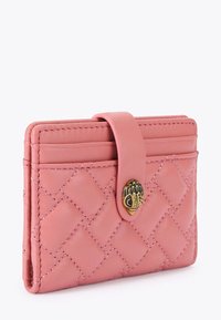 Portefeuille en cuir matelassé rose avec une fermeture à pression et un petit emblème décoratif en or à l'avant.