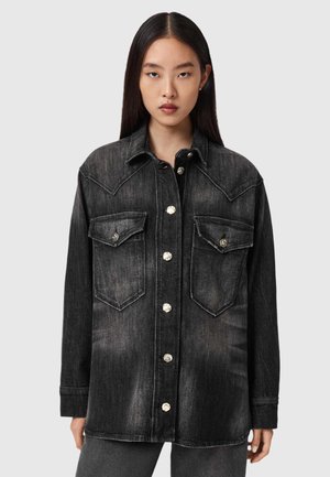 Czarna kurtka dżinsowa z zapinaniem na guziki z przodu, dwoma kieszeniami na piersi i srebrnymi detalami. Posiada klasyczny kołnierz i długie rękawy.