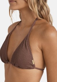 Top bikini marrone con texture, dotato di coppe triangolari, spalline sottili e regolabili e un piccolo logo dorato come dettaglio. Design minimalista.