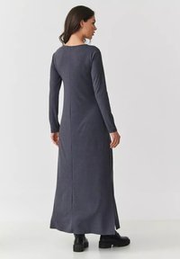 Długa, ciemnoszara sukienka maxi z długim rękawem, prostym krojem i bocznymi rozcięciami, wykonana z miękkiego, elastycznego materiału. Minimalistyczny design bez widocznych elementów metalowych.