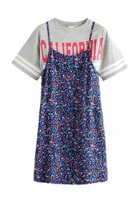 Graues T-Shirt mit "California" in Pink, das über einem marineblauen floralem Kleid mit verstellbaren Trägern liegt, das kleine, mehrfarbige Blumen zeigt.