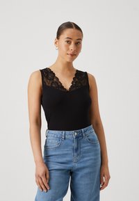 Bodysuit sans manches noir avec un bord en dentelle élaboré le long de l'encolure, associé à un jean en denim bleu clair taille haute. Texture douce.
