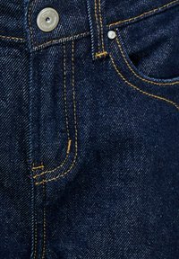 Temno modri jeans z zlato nitjo. Vključen je kovinski gumb in sprednji žep. Tekstura je gladka z rahlim leskom.