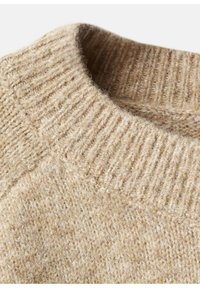 Beige gestrickter Pullover mit einem gerippten Kragen, der eine weiche Textur und subtile Farbvariationen aufweist und das Wollmaterial zur Geltung bringt.