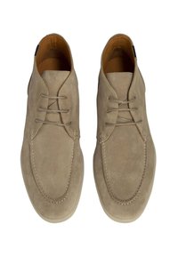 Zapatos de ante beige con un acabado suave. Presentan una puntera redondeada, diseño de cordones con cuatro ojales y suela de goma de color claro.