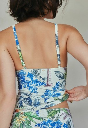 Kukka-kuvioinen yläosa, jossa sinisiä ja vihreitä trooppisia kuvioita. Kangas on pehmeää ja siinä on ohuet olkaimet, jotka luovat takaa istuvan siluetin.