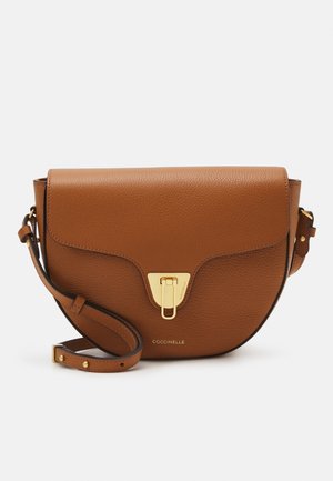 Bruine leren crossbodytas met gebogen klep, gouden sluiting, verstelbare riem en "Coccinelle" logo middenvoor.