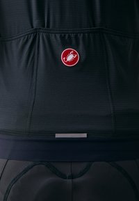 Maglia da ciclismo nera texturizzata sul retro con un logo circolare rosso che presenta uno scorpione bianco al centro, sopra una fascia scura.