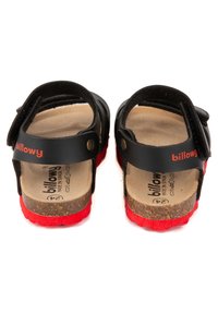 Sandales en cuir noir avec semelles en caoutchouc rouge, présentant des sangles ajustables et une semelle en liège, conçues pour le confort et la durabilité.