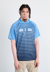 Nike polo shirt with light blue and dark blue horizontal stripes, featuring "AIR" in white font and a collar. Made of breathable fabric.