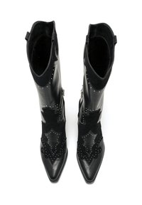 Botas de cuero negro y ante con punteras puntiagudas, que presentan costuras decorativas, tachuelas de plata y patrones intrincados en los cañones.