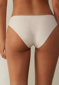 Beige sömlösa underkläder med en mjuk och slät textur. Har en låg midja och en lätt böjd baksida för komfort och täckning.