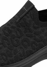 Fekete slip-on cipők texturált kötött felsőrésszel, finom mintázattal. Rugalmas hátsó panel és fekete gumitalp.