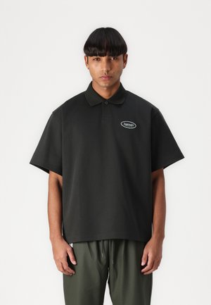 Polo noir avec une coupe décontractée, des manches courtes et un col. Dispose d'un petit logo en patch sur la zone de la poitrine gauche.