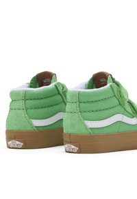 Gröna hög-top sneakers i mocka och kanvasmaterial, med vita sidoster och bruna logotags. Har en sula i gummigummi.