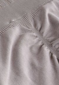 Elastično, svijetlosivo tkanje s rebrastom teksturom i naboranim detaljima; mekana, glatka površina s suptilnim naglascima šavova.