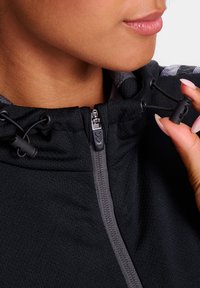 Zwarte hoodie met een ritssluiting aan de voorkant, voorzien van grijze accenten, verstelbare koordjes en een geweven stofmix. Close-up van de halslijn.