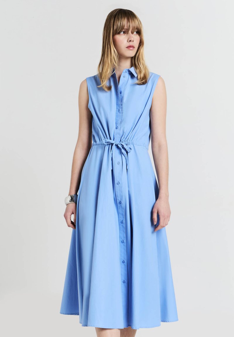 Blaues ärmelloses Hemdblusenkleid mit elastischem Taillengürtel, fließendem Rock und glatter Stoffoberfläche.