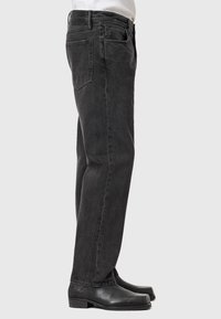 Sorte denimjeans med lige pasform, der har fem lommer, bæltestropper og en subtil, falmet tekstur, parret med sorte sko.