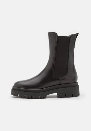 Bottines en cuir noir à panneaux latéraux élastiques, semelle en caoutchouc noire épaisse, texture lisse et design à bout arrondi.