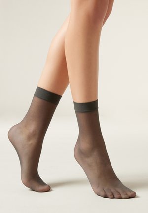 Svarta, genomskinliga ankelsockor med en solid mörk kant upptill, designade för en skräddarsydd, elegant look. Mjukt, lätt material som framhäver fötterna.