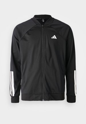 Schwarze Sportjacke mit einem Frontreißverschluss, Raglanärmeln, weißem Adidas-Logo und weißen Streifen an den Ärmeln. Glattes Gewebe mit elastischen Bündchen.