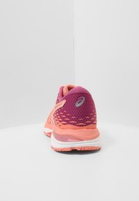 Scarpe da corsa con una tomaia in mesh rosa e viola, tallone testurizzato e accenti arancioni a contrasto. Presentano suola ammortizzata e dettagli con logo.