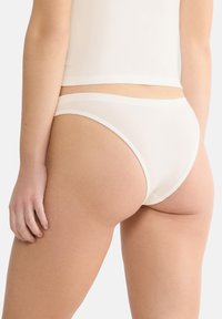 Witte katoenen ondergoed met een dunne, elastische tailleband en een naadloos ontwerp, met een lichte glans en een gladde textuur.