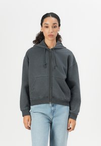 Dark gray zip-up hoodie with a hood, kangaroo pocket, and ribbed cuffs. Soft fabric with a relaxed fit and visible stitching details.