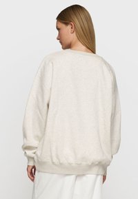 Hellbeige Sweatshirt aus weichem Stoff, mit lockerer Passform, gerippten Bündchen und Saum, in einem minimalistischen Design.