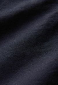 Tejido azul marino oscuro con una textura suave y un ligero brillo, mostrando variaciones sutiles en color y sombra a lo largo de la superficie.