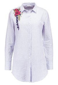 Camisa de manga larga a rayas azul y blanca con detalles florales bordados en el hombro izquierdo. Material de algodón, corte relajado.