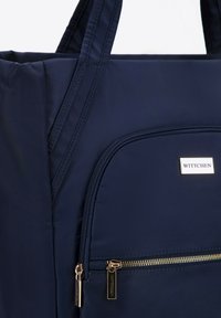 Granatowa torba tote wykonana z nylonu, z przednią kieszenią na zamek błyskawiczny, złotymi detalami i podwójnymi uchwytami u góry. Teksturowana powierzchnia.