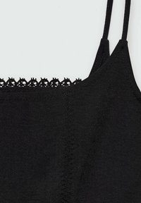 Camisole noire à fines bretelles, ornée d'une bordure en dentelle le long du décolleté, confectionnée dans un tissu lisse avec des détails de coutures visibles.