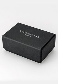 Boîte rectangulaire noire avec une surface texturée, portant le texte blanc "LIEBESKIND BERLIN" centré sur le couvercle.