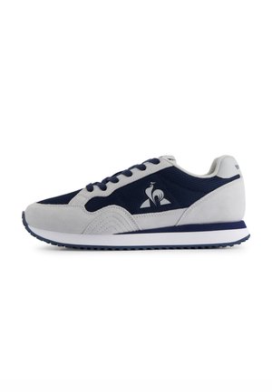Baskets de sport grises et bleu marine en matériaux en suède et en maille, avec une semelle intermédiaire blanche rembourrée et un logo sur le côté.