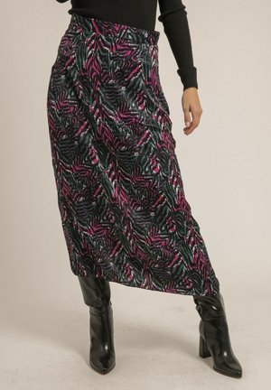 Jupe enveloppante à motifs noir et rose, fabriquée dans un tissu texturé, ornée de grands motifs de feuilles abstraites. Associée à des bottes noires montantes.