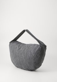 Grå stoffpose med en krøllet tekstur, rund form og to flate håndtak. Har en glidelås-lukking. Enkle og funksjonelle design.