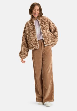 Bruine fleecjas met bladpatroon, cropped ontwerp, hoge kraag; gecombineerd met lichtbruine corduroy broek en witte sneakers.