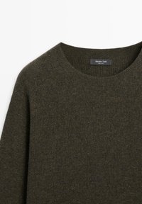 Mørkegrønt striktrøje med rund halsudskæring og en blød tekstur. Etiket indeni læser "Massimo Dutti," som angiver mærket og oprindelsen.