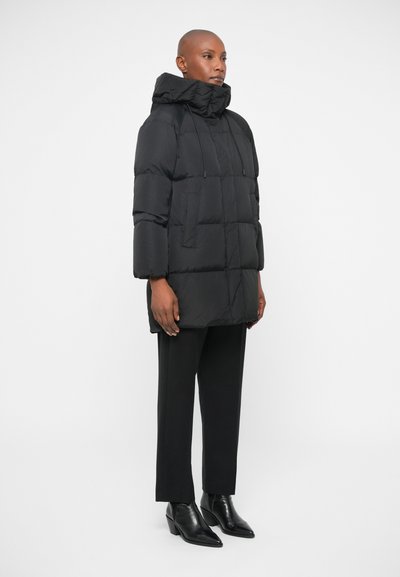 Μαύρο μπουφάν πούφ με κουκούλα, σε ορθογώνιο σχήμα και με ραβδωτή υφή. Διαθέτει μπροστινές τσέπες και κορδόνι ρύθμισης για προσαρμοσμένη εφαρμογή.