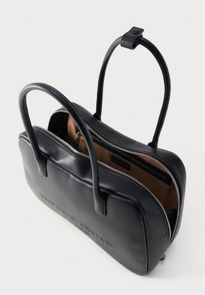 Μαύρη δερμάτινη τσάντα χειρός σε ορθογώνιο σχήμα με δύο λαβές, μερικώς ανοιχτό φερμουάρ που αποκαλύπτει μπεζ εσωτερικό και κρυφό εσωτερικό φερμουάρ τσέπης.